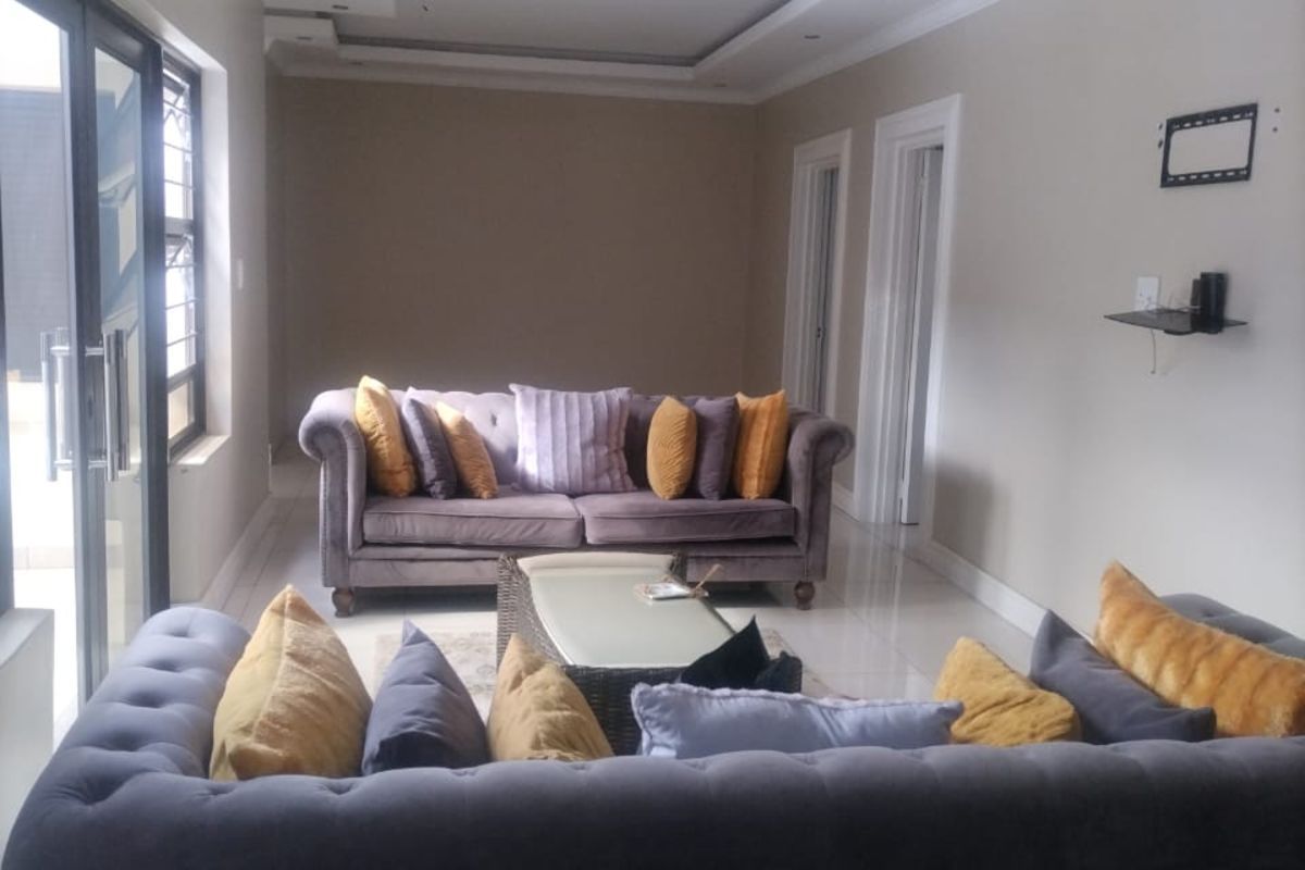 A spacious living room featuring tiled flooring, recessed ceiling lighting, and large sliding glass doors providing access to the exterior.