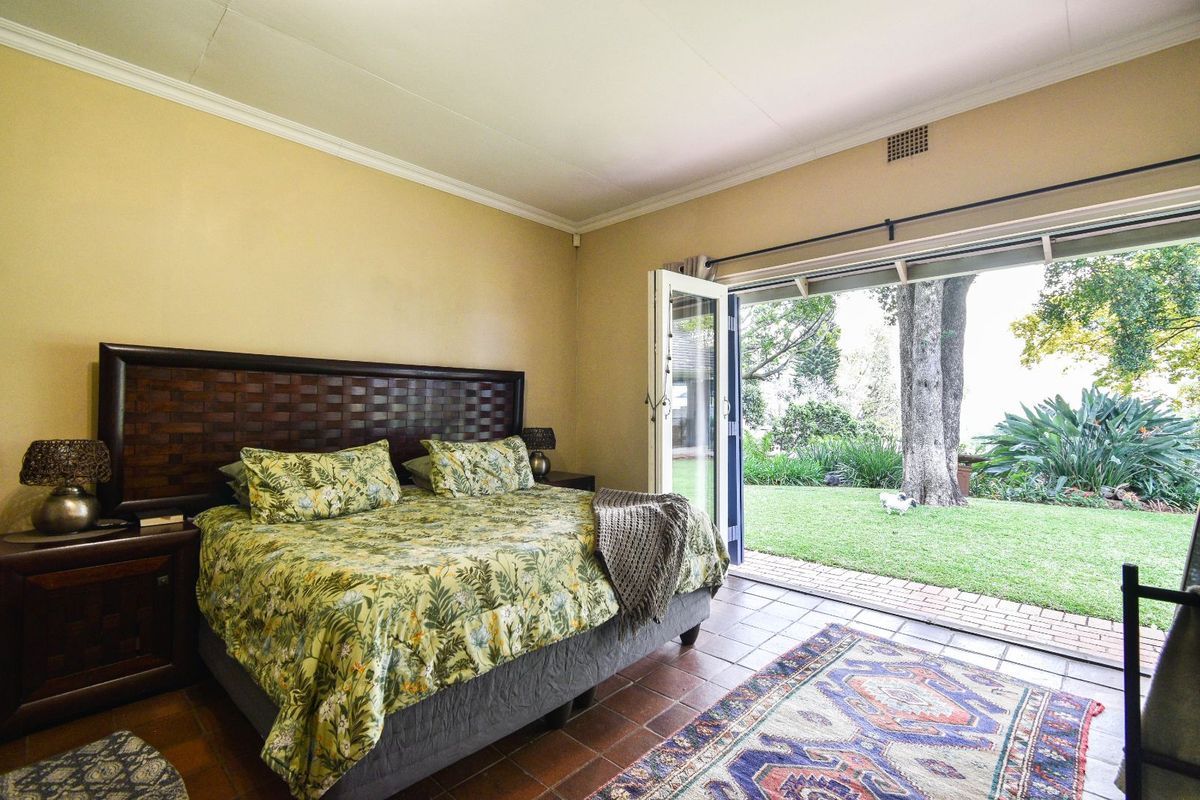 Spacious bedroom featuring tiled flooring, crown molding, and large glass double doors opening directly onto a private garden patio.