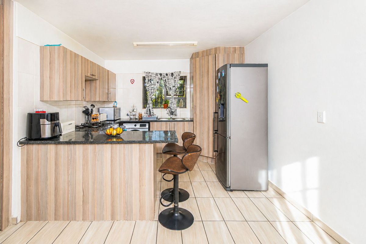 Functional kitchen featuring light wood-look cabinetry, granite countertops, a breakfast bar, and tiled flooring, providing a practical and well-organized cooking space.