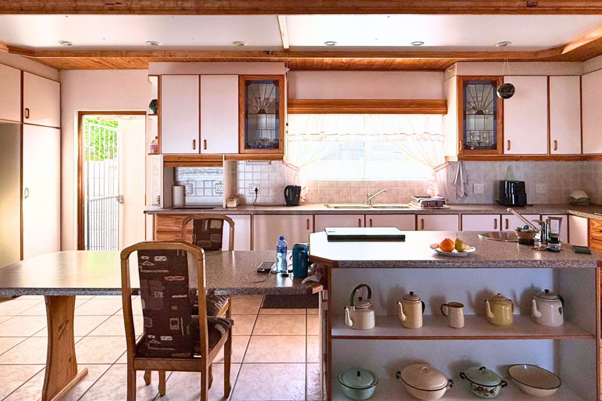 Spacious kitchen featuring a central island with integrated breakfast bar, ample cabinetry, tiled flooring, and direct access to an outdoor area.