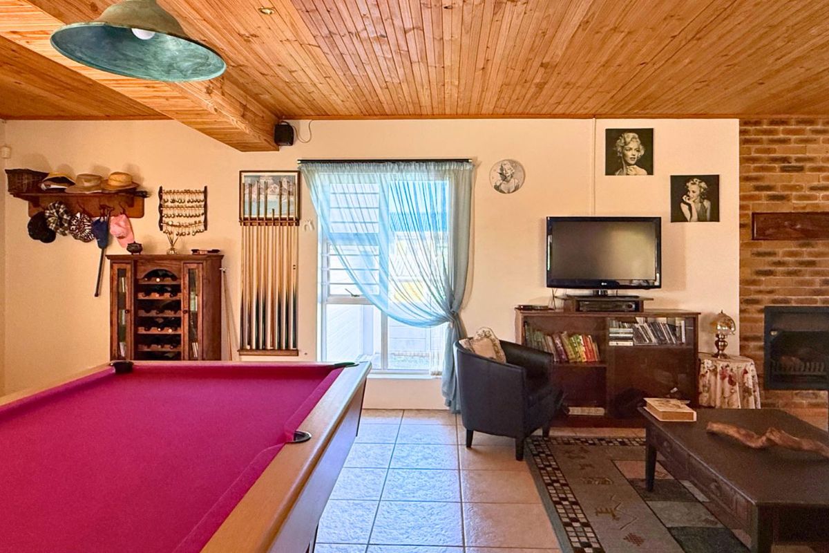 Spacious living area featuring a built-in fireplace with brick surround, timber-clad ceiling, and tiled flooring, currently utilized as a recreational space.
