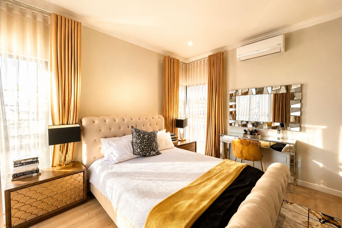 A well-appointed bedroom featuring light wood-look flooring, recessed downlighting, and a wall-mounted air conditioning unit.