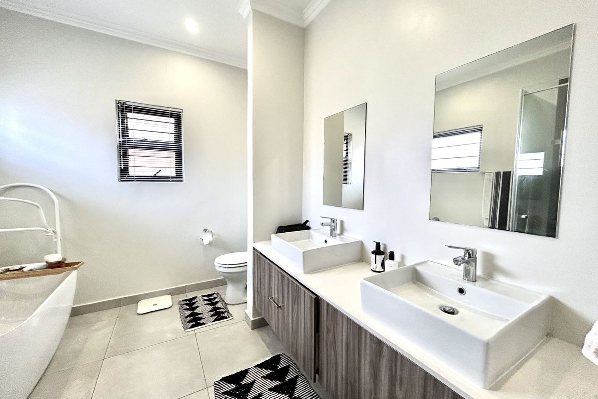 Modern bathroom featuring a double vanity with vessel sinks, a freestanding bathtub, and tiled flooring.