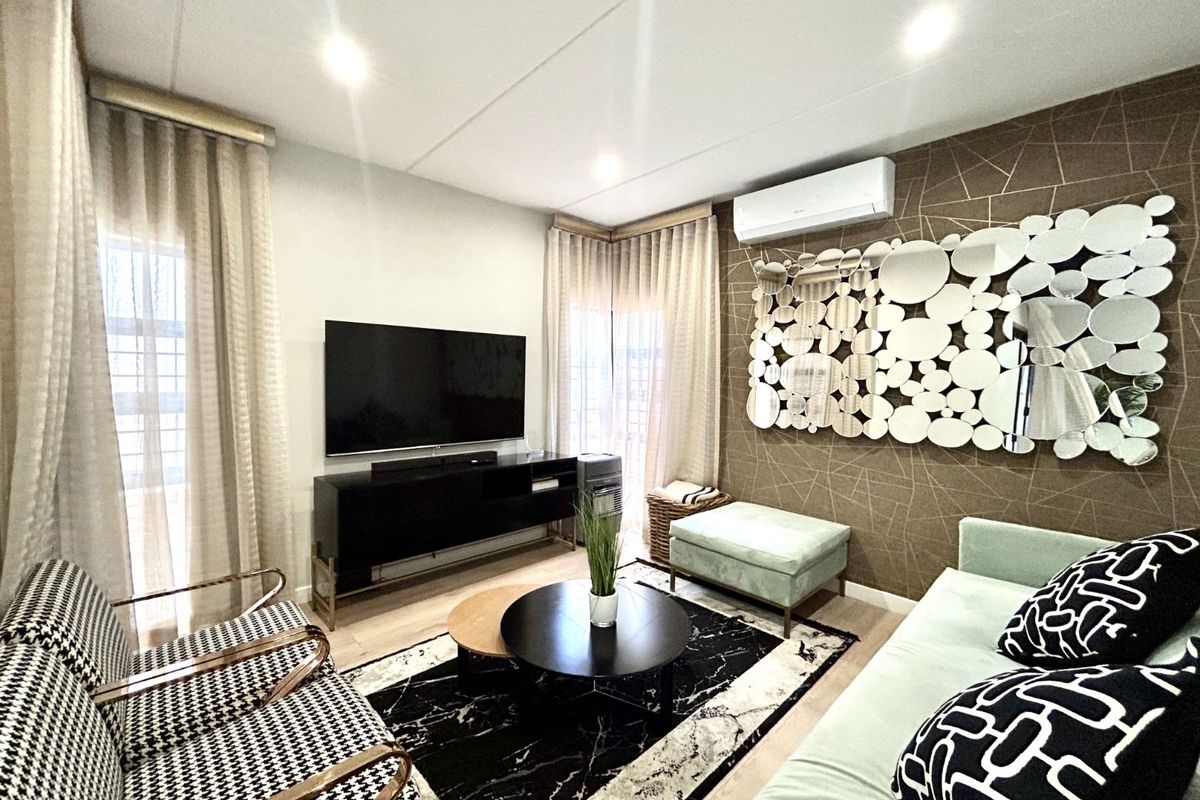 A well-maintained living room featuring a decorative accent wall, recessed ceiling lighting, and a wall-mounted air conditioning unit.