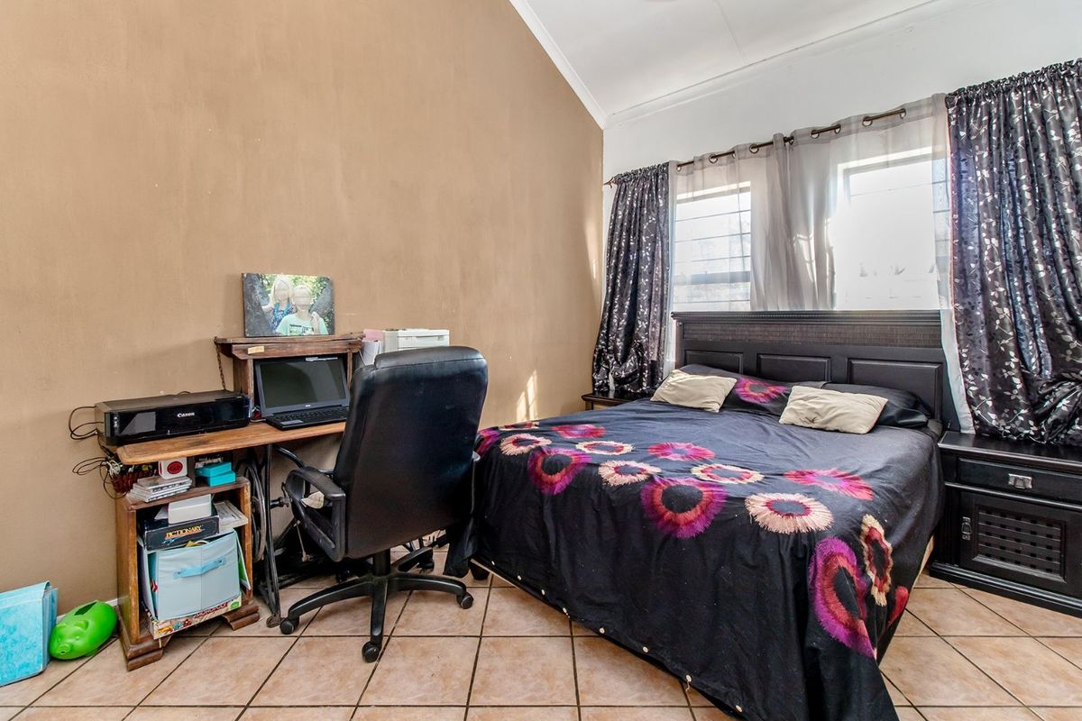 A bedroom featuring vaulted ceilings, tiled flooring, and large windows with curtain fixtures.