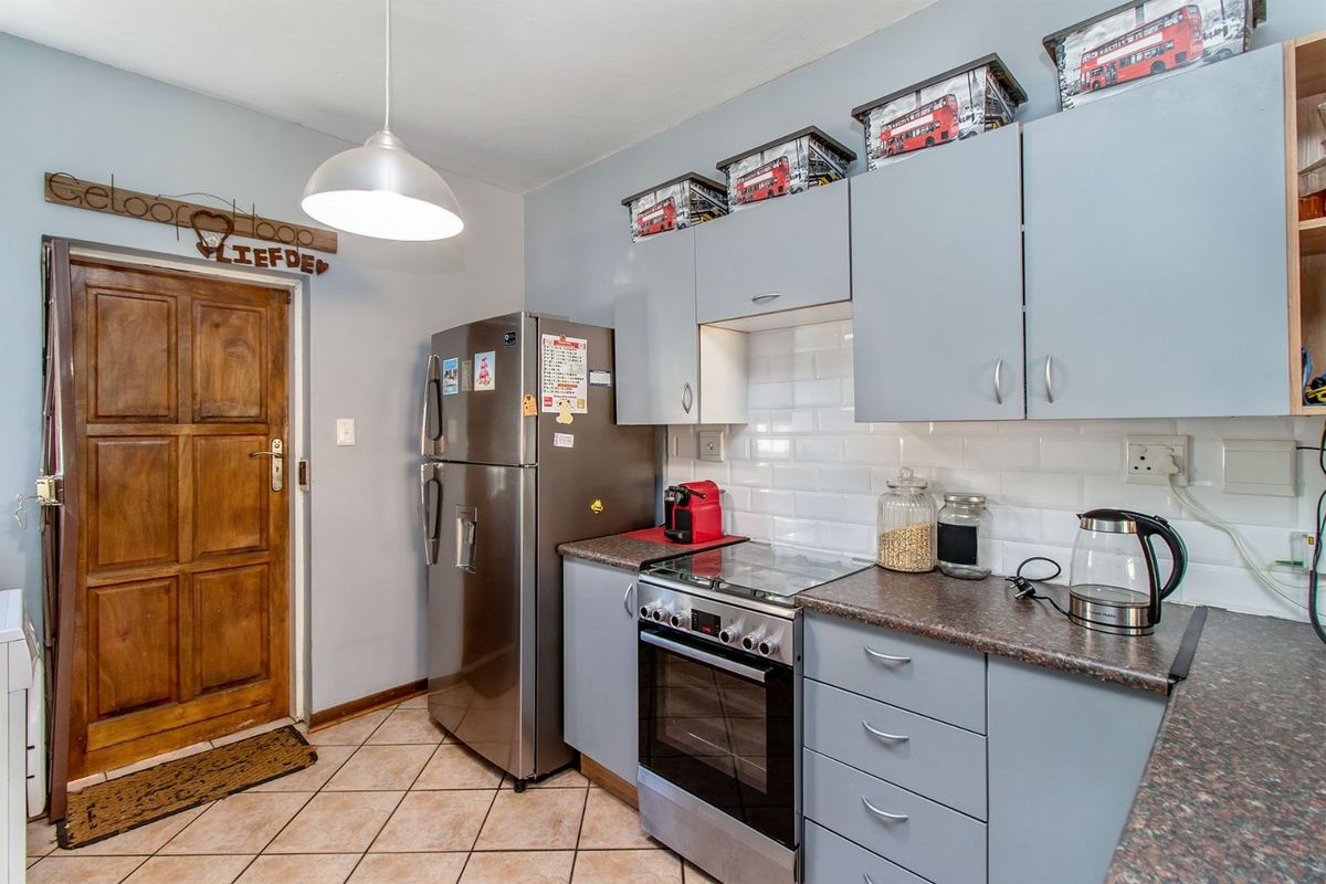 A functional kitchen featuring light grey cabinetry, a subway tile backsplash, stone-look laminate countertops, and a built-in oven with a glass cooktop.