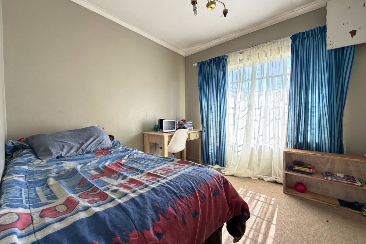 A bedroom featuring carpeted flooring, a window with curtain treatments, and a central ceiling light fixture.