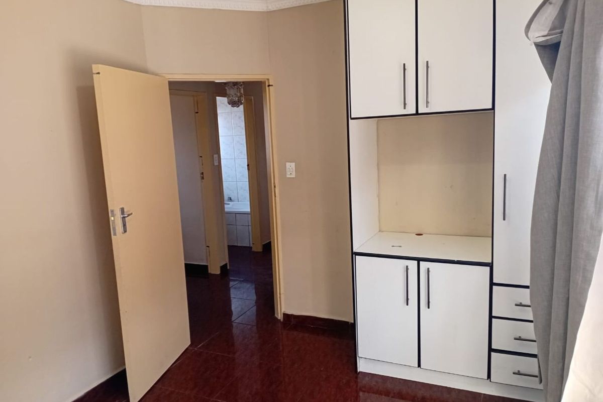 A bedroom featuring built-in white cabinetry with dark trim, tiled flooring, and direct access to an adjacent bathroom.