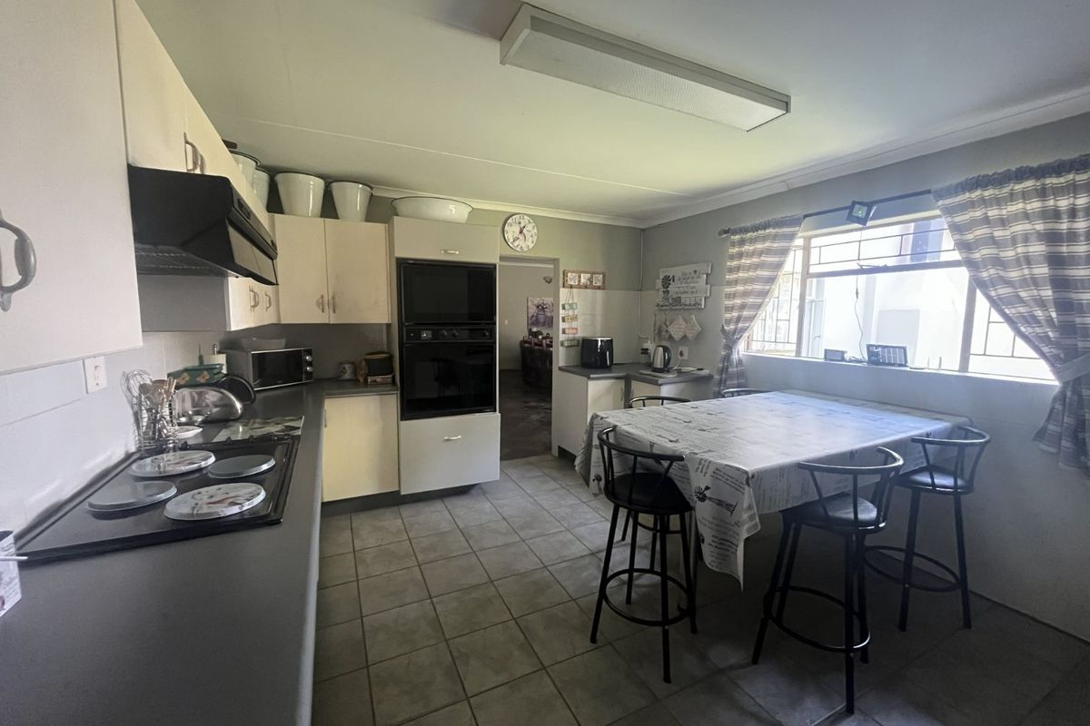 A functional kitchen featuring built-in cabinetry, a wall-mounted oven, an extractor fan, and a tiled floor with an integrated dining area.