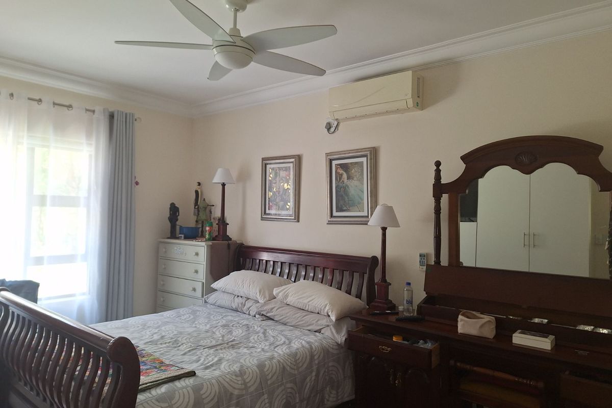 A well-maintained bedroom featuring a ceiling fan, wall-mounted air conditioning unit, and crown molding.