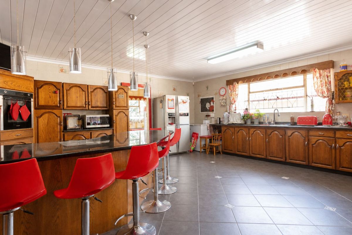 Spacious kitchen featuring traditional wooden cabinetry, a large central island with breakfast bar seating, and tiled flooring throughout.