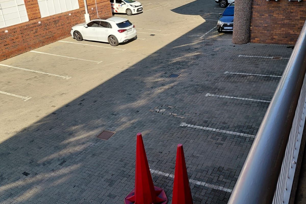 An elevated view of an office building parking area featuring paved bays and brick facade architecture.