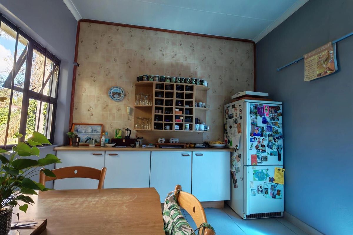 A functional kitchen area featuring built-in cabinetry, tiled splashback, and ample counter space, illuminated by natural light from the adjacent window.