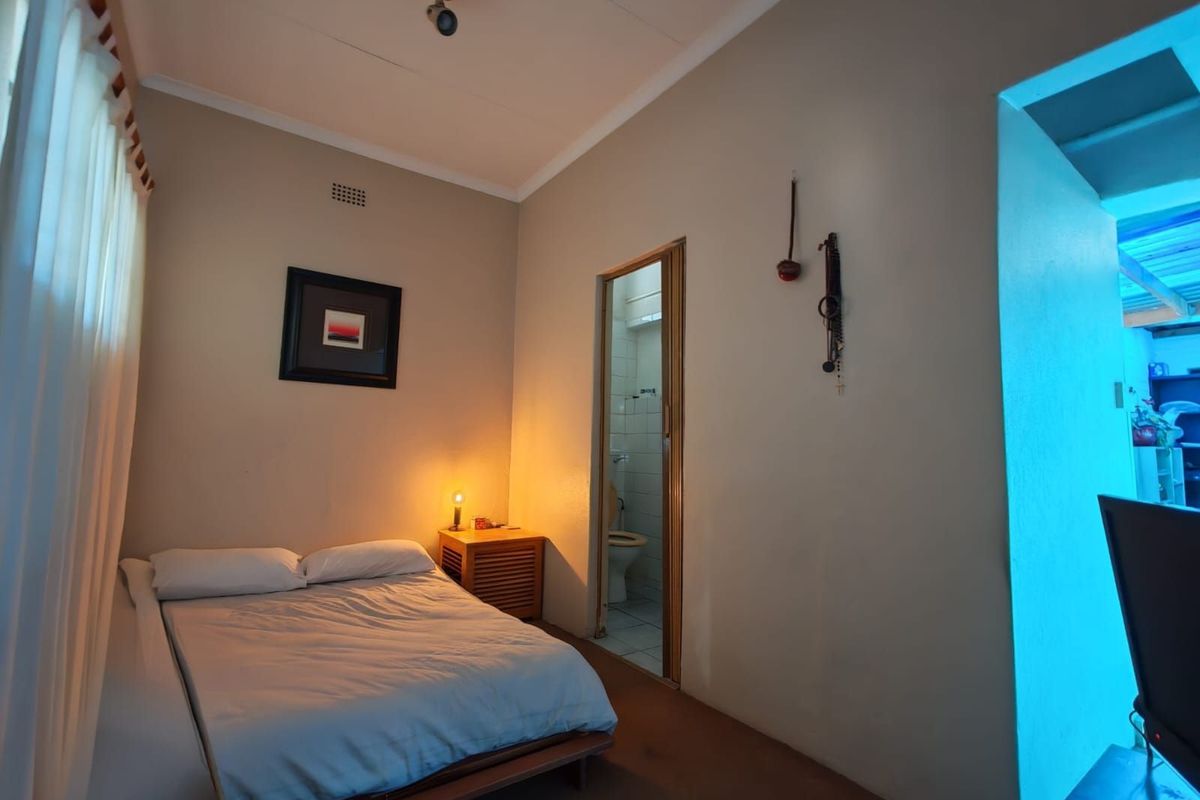 A bedroom featuring an en-suite bathroom, neutral wall finishes, and standard lighting fixtures.