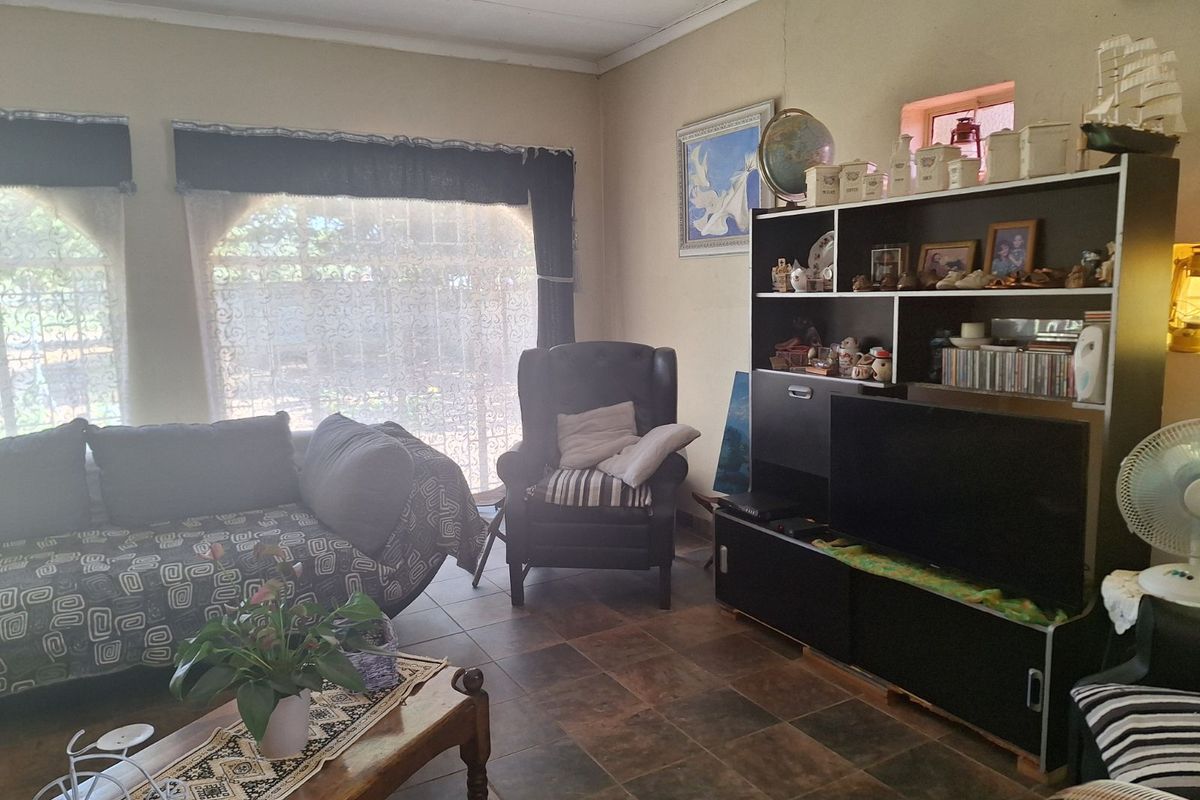 A living room featuring tiled flooring and large windows with security bars, offering a functional space with potential for modernization.