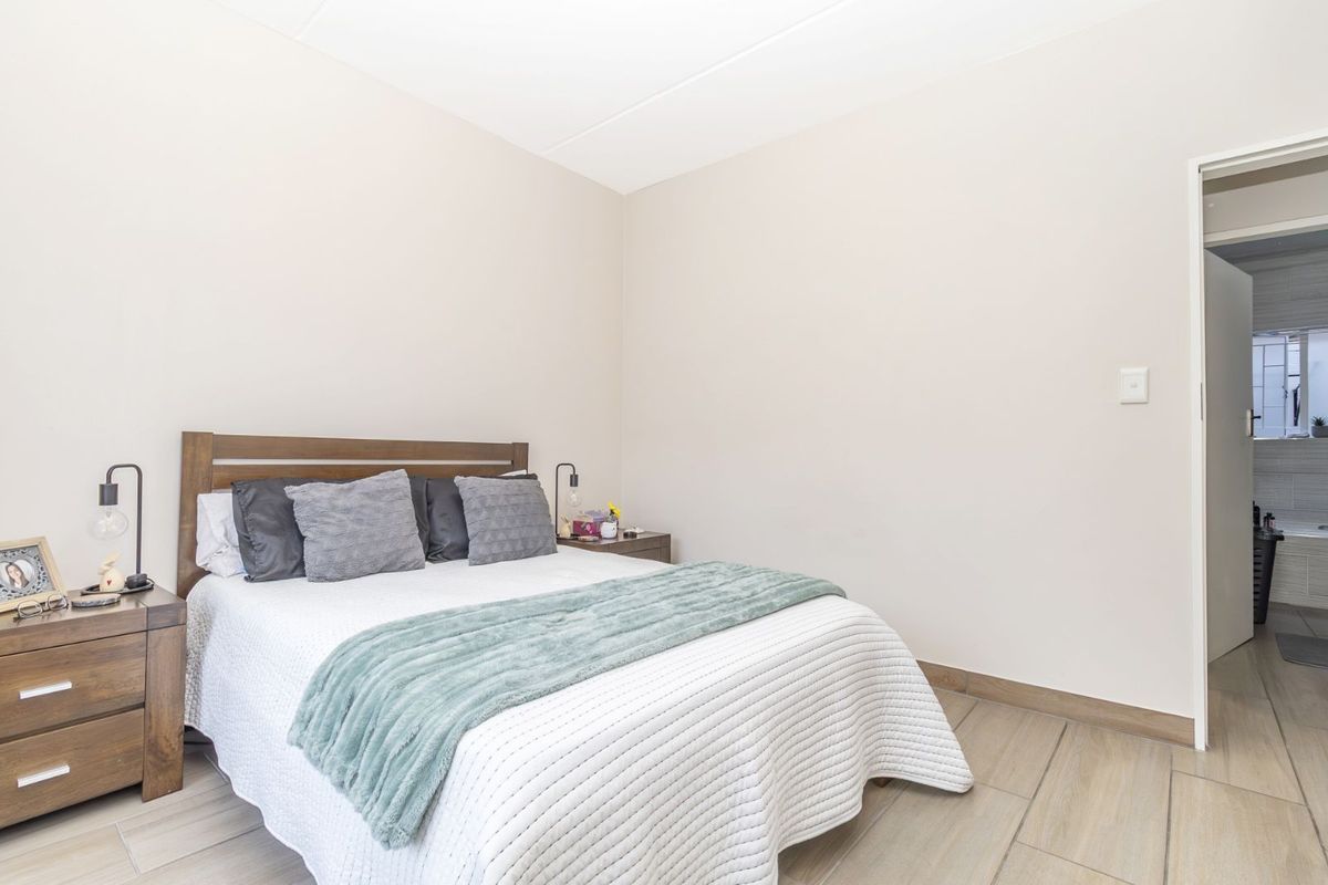 A well-maintained bedroom featuring neutral wall tones, tiled flooring, and an adjoining bathroom entrance.