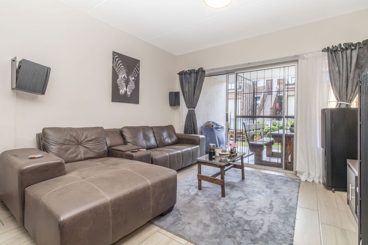 A comfortable living room featuring tiled flooring and large sliding glass doors that provide direct access to an outdoor patio area.