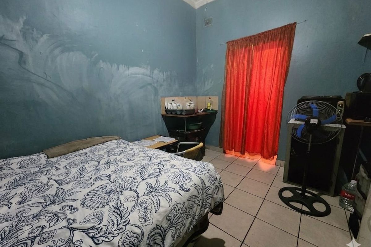 A bedroom featuring tiled flooring and blue painted walls, providing a functional living space with direct access to an outdoor area.