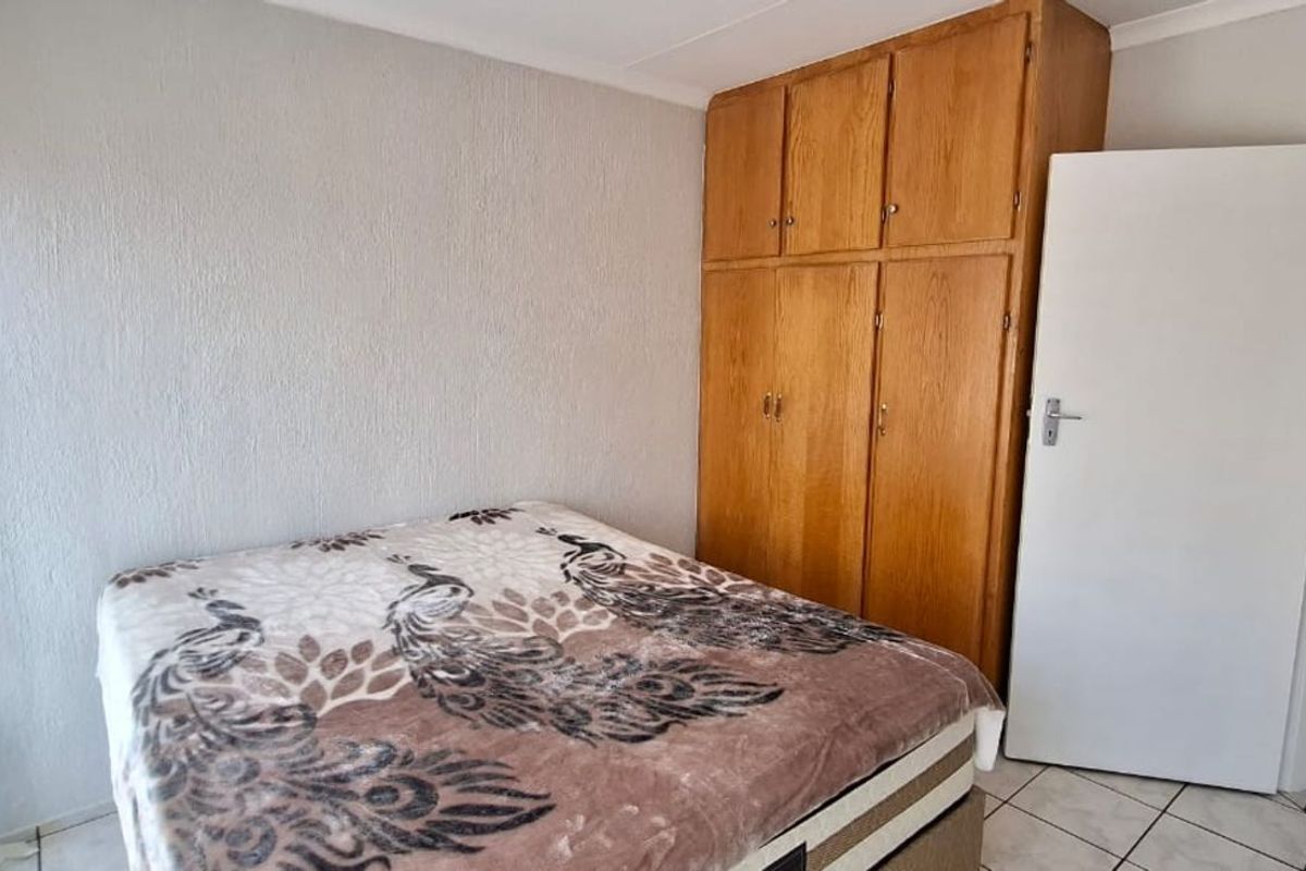 A bedroom featuring built-in wooden cupboards and tiled flooring, providing functional storage space.