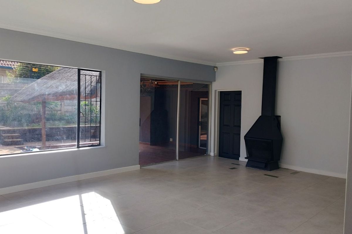 Spacious living room featuring large windows, tiled flooring, and a modern black freestanding fireplace, offering a bright and neutral living space.