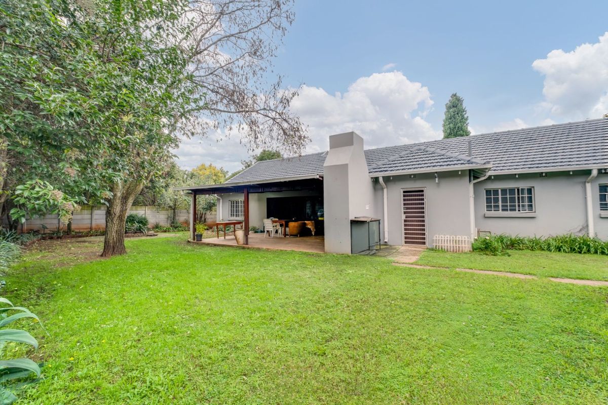 A spacious rear garden featuring a covered patio area with a built-in fireplace, perfect for outdoor entertaining and relaxation.