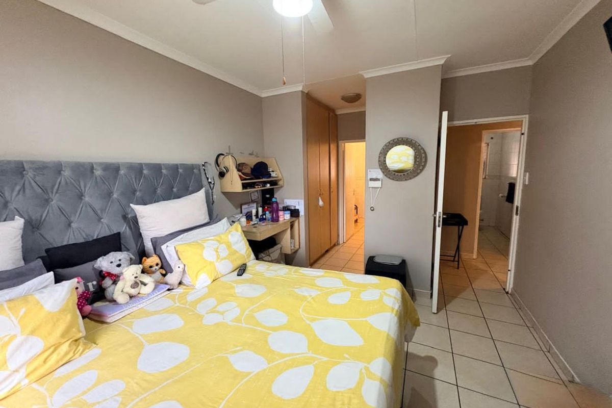 A bedroom featuring built-in cupboards, tiled flooring, and a ceiling fan, with direct access to an en-suite bathroom.