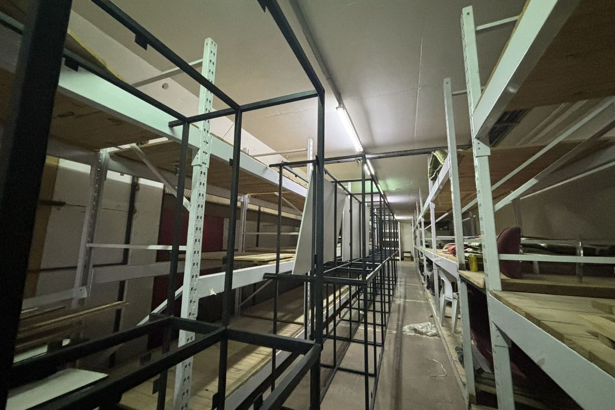 A functional utility storage space featuring extensive industrial-style metal shelving units and overhead fluorescent lighting, suitable for inventory or equipment storage.