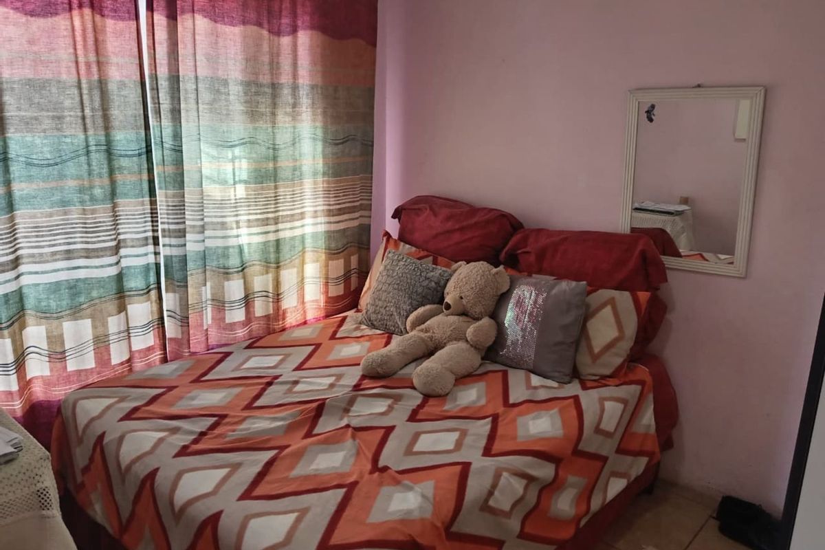 A bedroom featuring tiled flooring and a wall-mounted mirror.