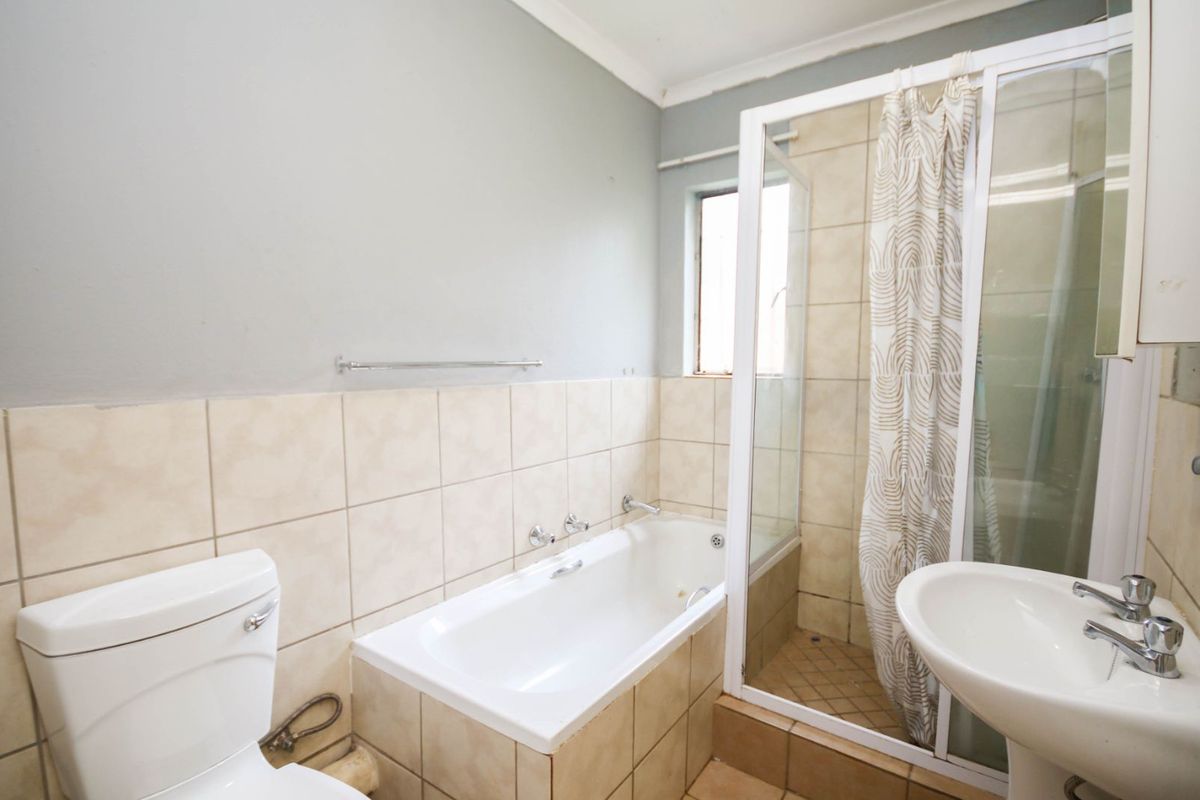 A functional bathroom featuring a built-in bathtub, a separate shower enclosure with a glass door, a pedestal basin, and a standard toilet.