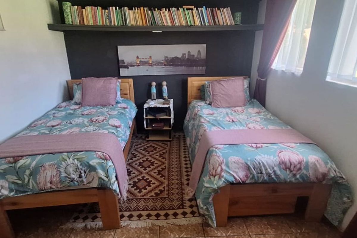 A cozy bedroom featuring a built-in floating shelf above the bed area, tiled flooring, and natural light from the side windows.