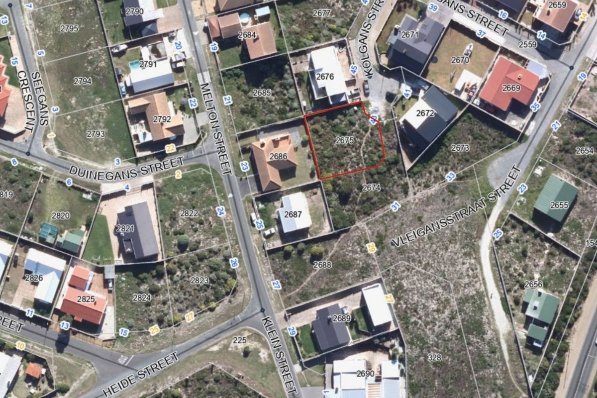 An aerial view of a vacant residential plot in a developed neighborhood, showing the property boundaries and surrounding street layout.