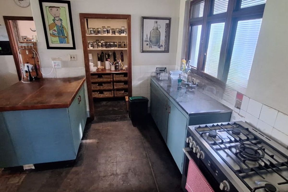 A functional kitchen featuring a gas stove, stainless steel countertop, and a dedicated walk-in pantry area with built-in shelving.