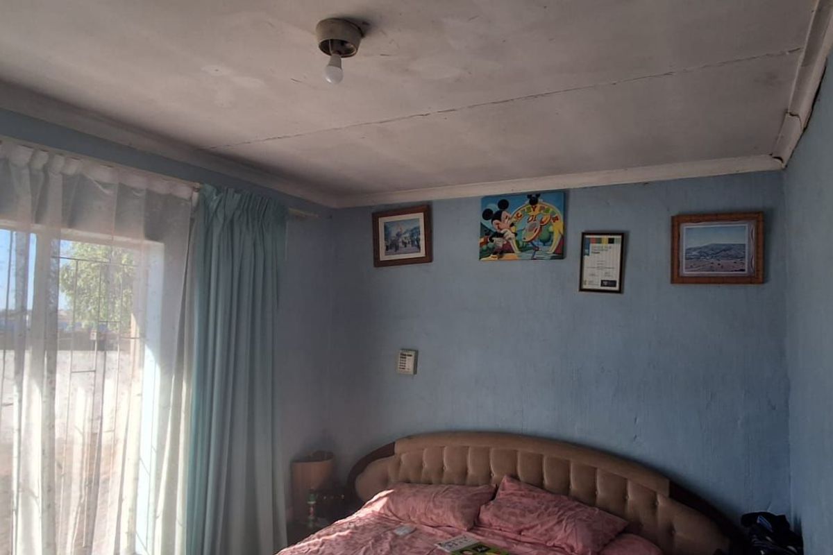 A bedroom featuring a large window with security bars, standard ceiling finish, and blue painted walls.