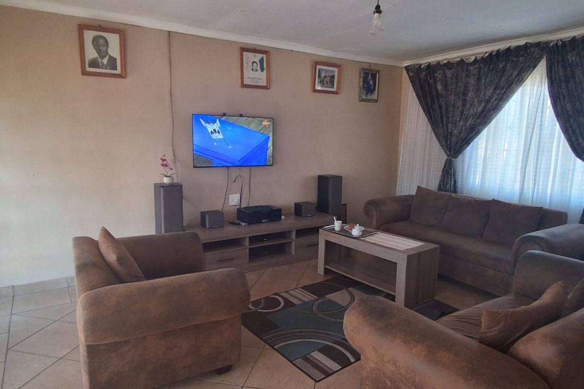 A comfortable living room featuring tiled flooring and large windows with curtains, providing a functional space for relaxation and entertainment.