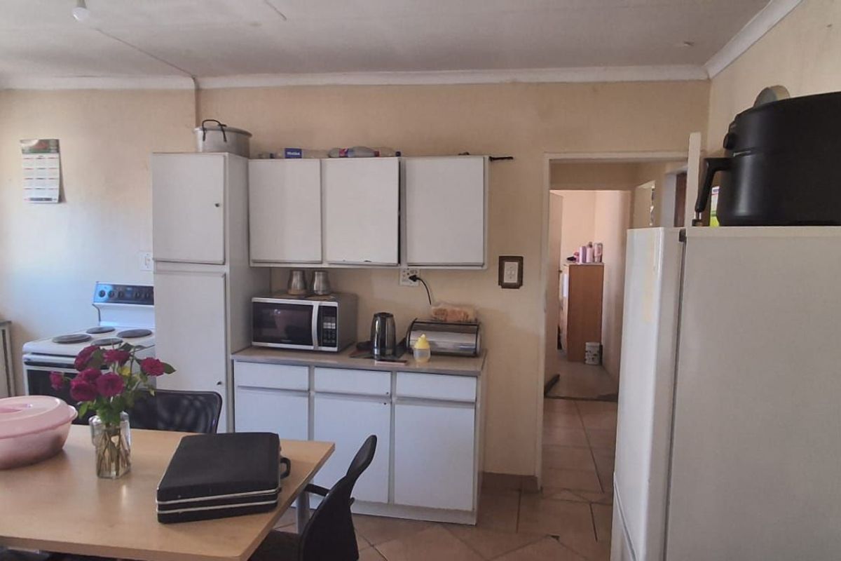 A functional kitchen featuring white cabinetry, tiled flooring, and a dedicated dining area, offering a practical layout for daily meal preparation.