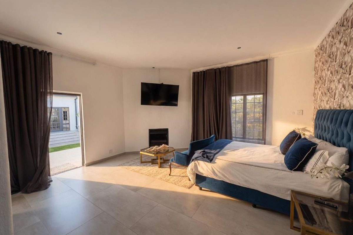 Spacious bedroom featuring large format floor tiles, a built-in fireplace, and direct access to an outdoor patio area.
