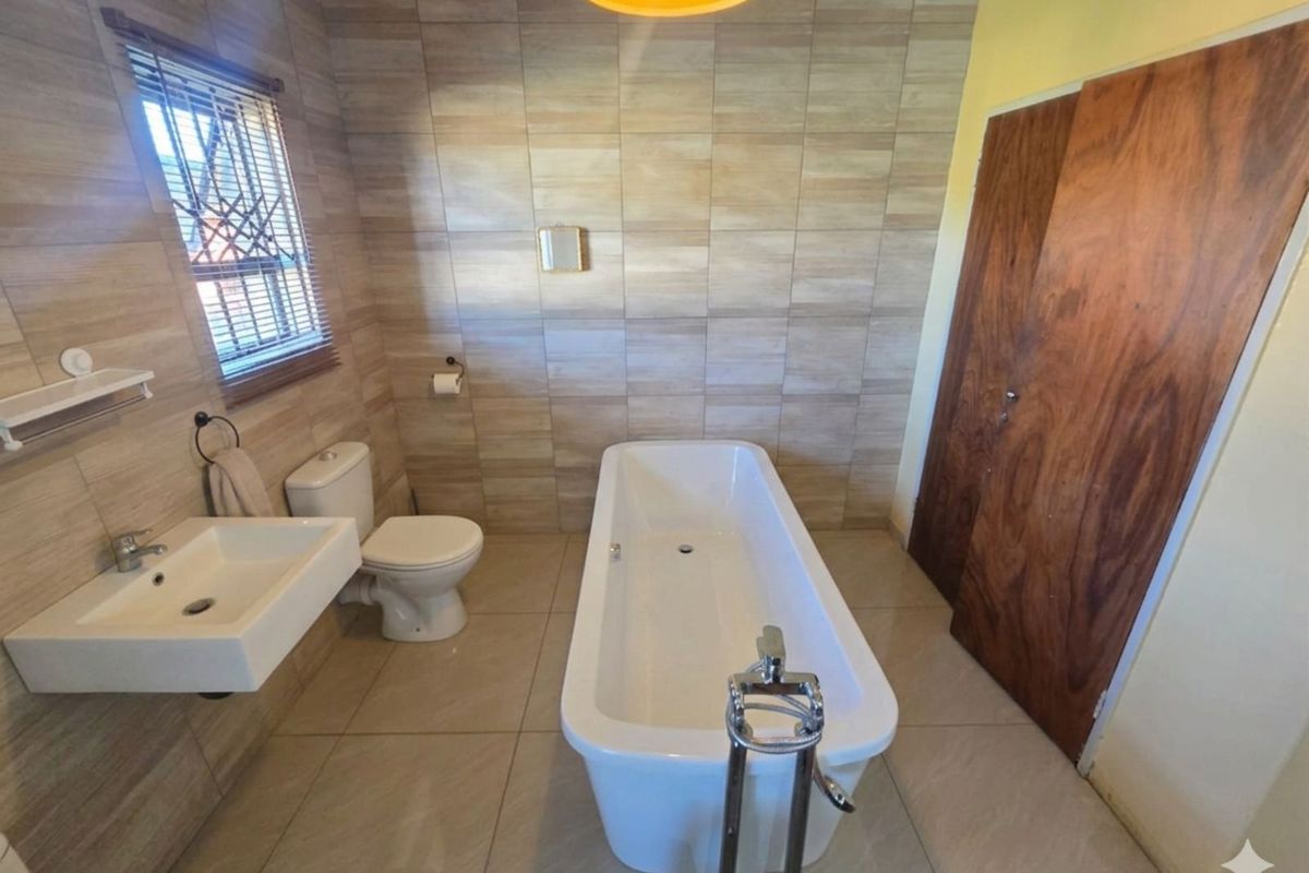 A modern bathroom featuring floor-to-ceiling wood-look wall tiles, a freestanding bathtub with chrome floor-mounted mixer, wall-hung basin, and a close-coupled toilet.