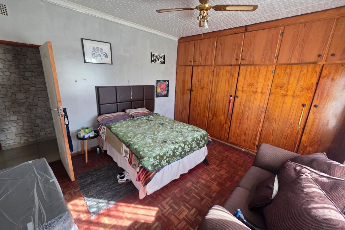 A bedroom featuring extensive built-in wooden cabinetry, parquet flooring, and a ceiling fan, offering ample storage space.