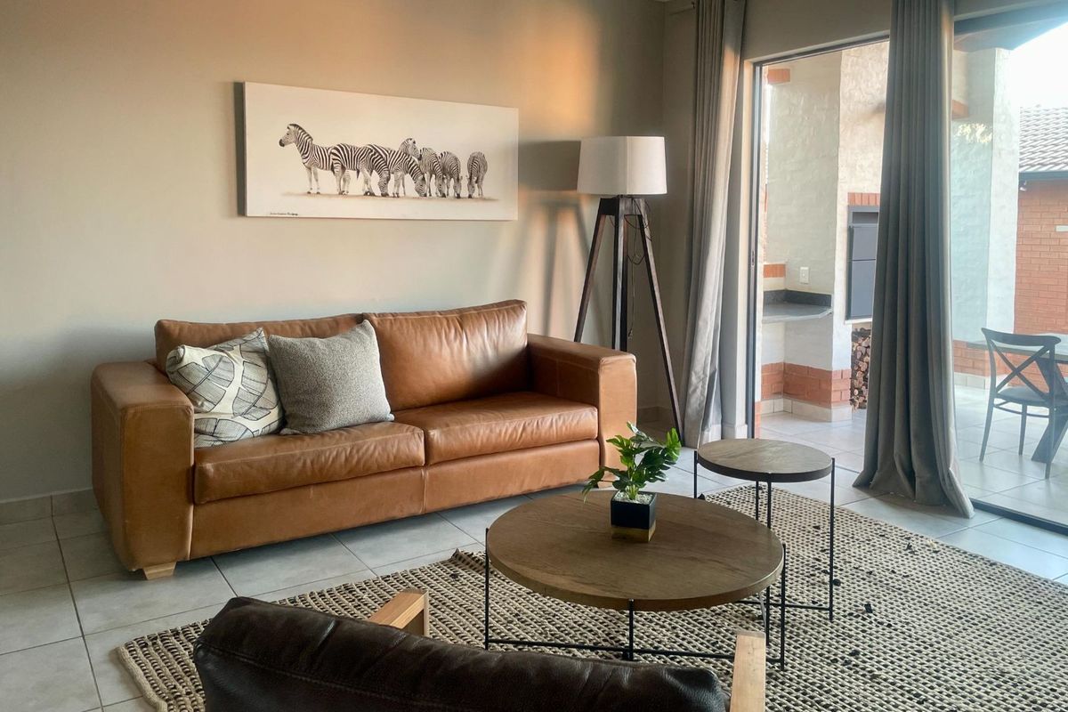 A comfortable living room featuring tiled flooring and large sliding glass doors that provide seamless access to an outdoor patio area.