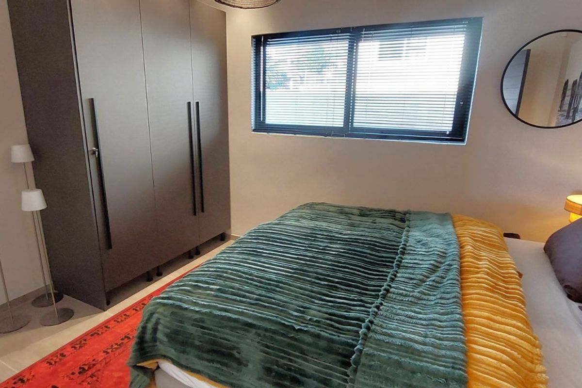 A well-maintained bedroom featuring built-in floor-to-ceiling cabinetry and modern window blinds, offering a clean and functional living space.