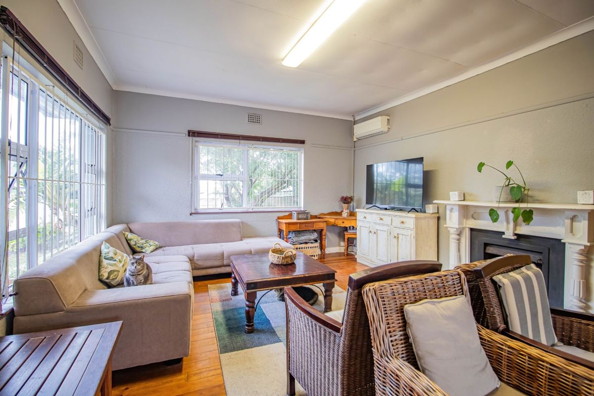 A comfortable living room featuring timber flooring, a classic fireplace mantel, and a wall-mounted air conditioning unit.
