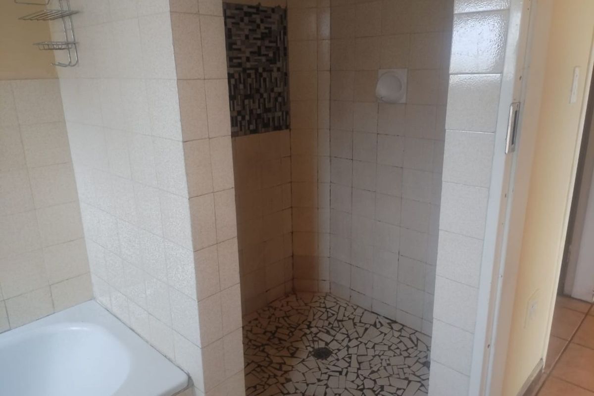 A bathroom featuring a tiled shower enclosure with a mosaic accent wall and a built-in bathtub.