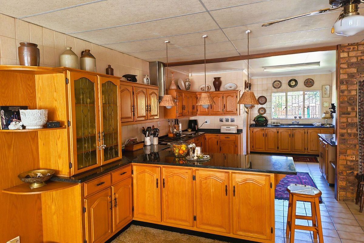 Spacious kitchen featuring extensive wooden cabinetry, granite countertops, a central island, and a secondary prep area with a sink.