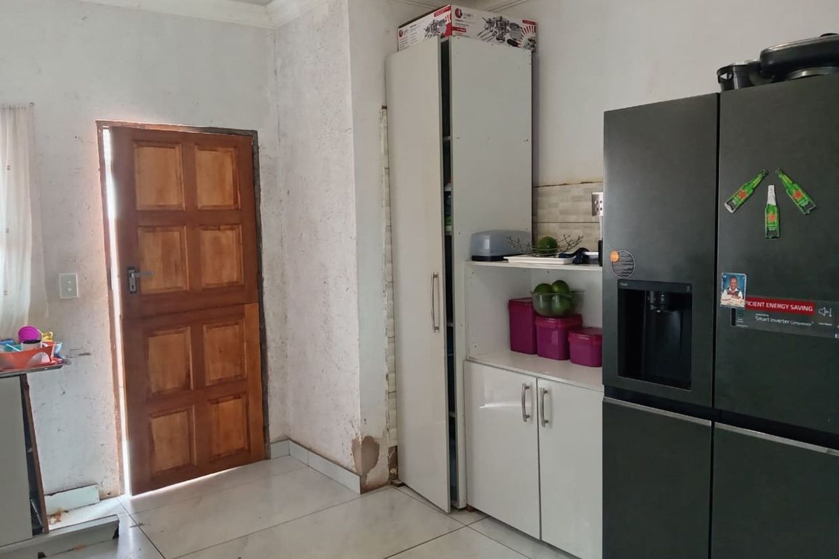 A functional kitchen area featuring built-in cabinetry, tiled flooring, and direct access to an exterior door.