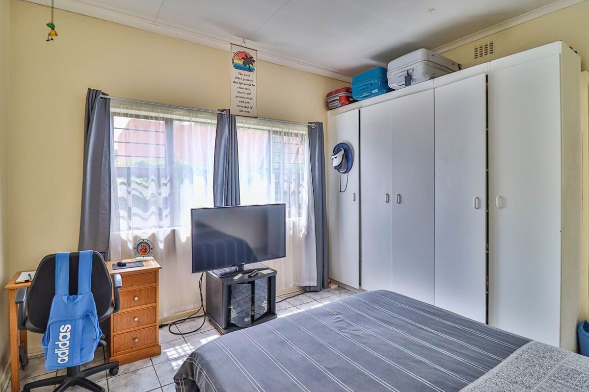 A functional bedroom featuring built-in wardrobes and tiled flooring, providing ample storage space and natural light.