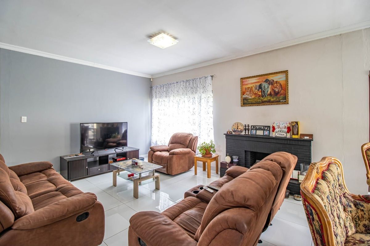 A comfortable living room featuring tiled flooring, a built-in fireplace, and large windows that provide ample natural light.