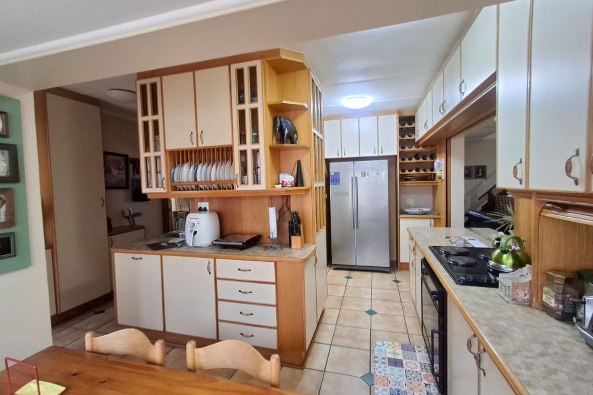 A functional kitchen featuring built-in cabinetry, integrated storage, tiled flooring, and a built-in hob and oven setup.
