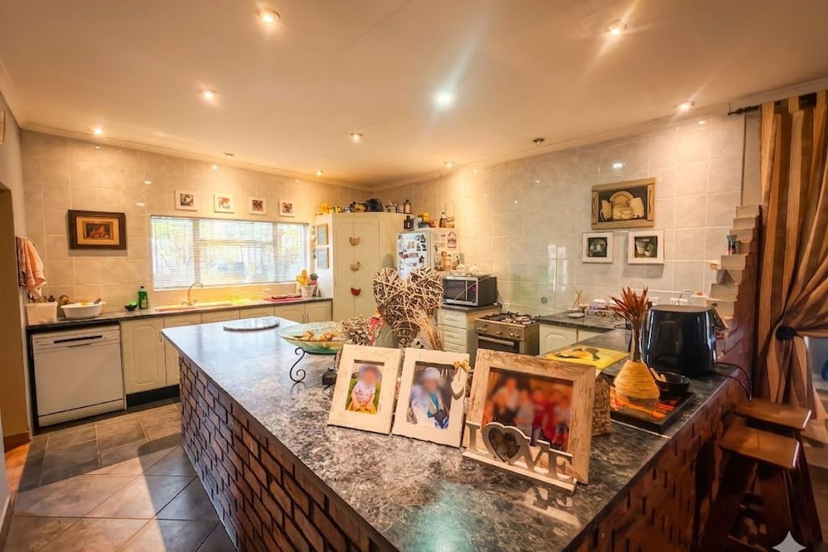 Spacious kitchen featuring a large central island with stone-look countertop, tiled walls, recessed lighting, and integrated cabinetry.