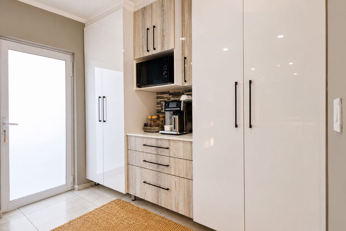 Modern kitchen cabinetry featuring a mix of high-gloss white and wood-grain finishes, integrated microwave, and sleek black hardware.