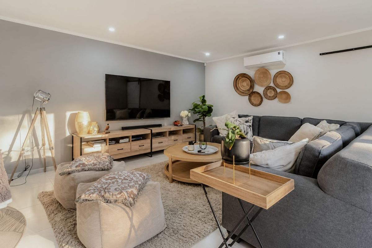 A well-presented living room featuring recessed downlighting, a wall-mounted air conditioning unit, and neutral wall finishes.